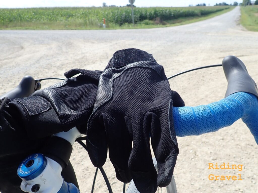 Cuero full fingered gloves on a handle bar in a rural setting